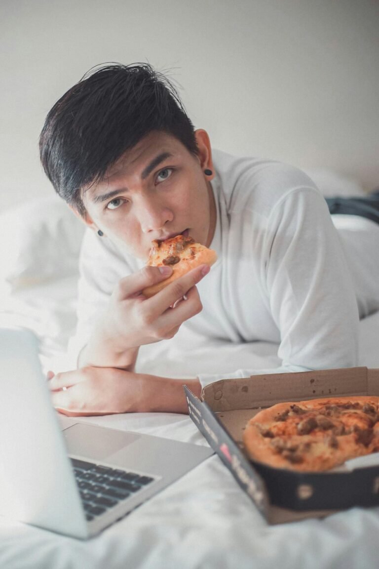 pexels-kenzero14-22042287 Young man eating pizza in front of laptop