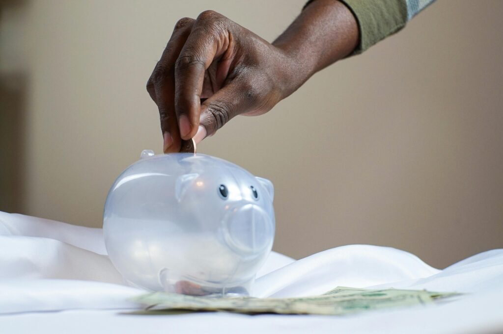 Image of a hand putting coins into a piggy bank
