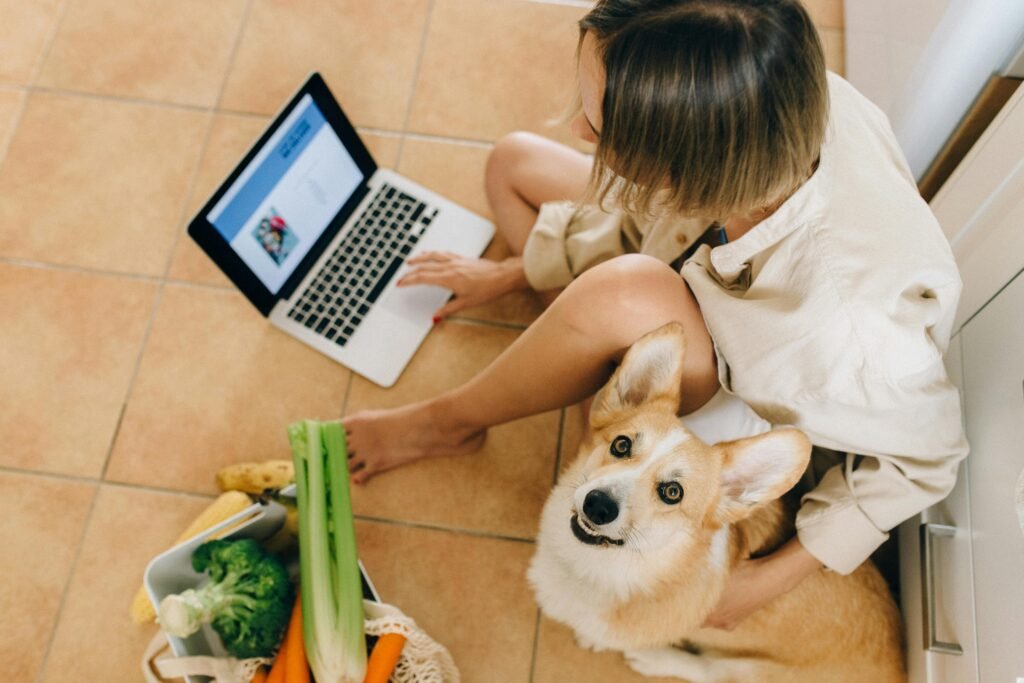 Woman with her dog sitting on the floor looking at computer