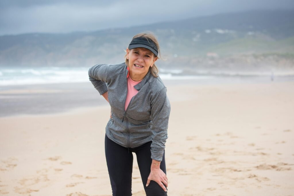 Woman on the beach holding her knew due to pain
