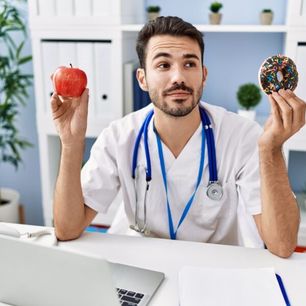doctor at his desk with apple and donut in each hand