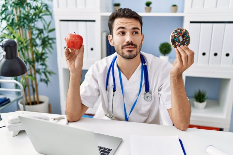 doctor at his desk with apple and donut in each hand