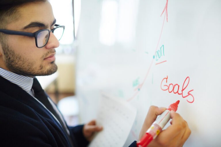 Man writing his goals on white board