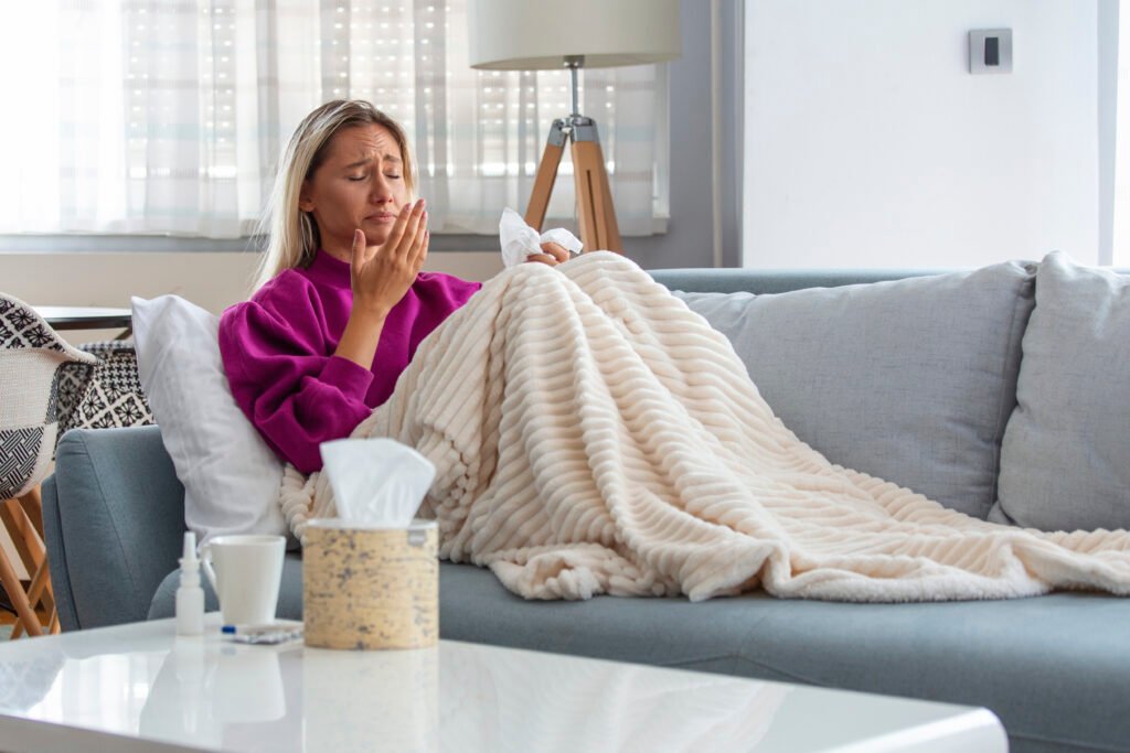 Woman on a couch under blanket beating flu