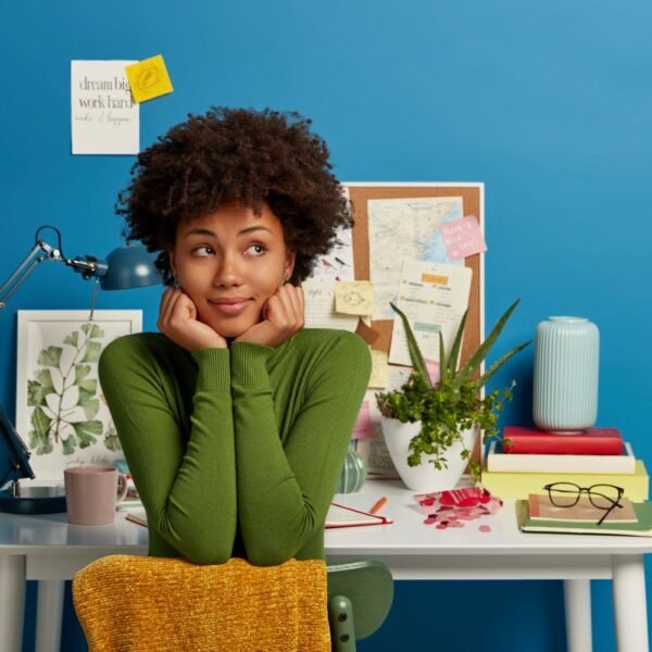 young woman in from of a small table in her room thinking about improving herself