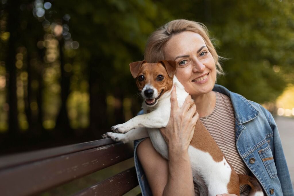 Woman sitting on a park bench and holding her small healthy dog