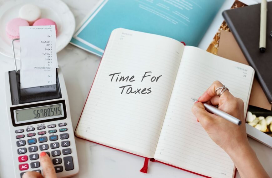 A person writing time for taxes in their journal which is on a table next to calculator