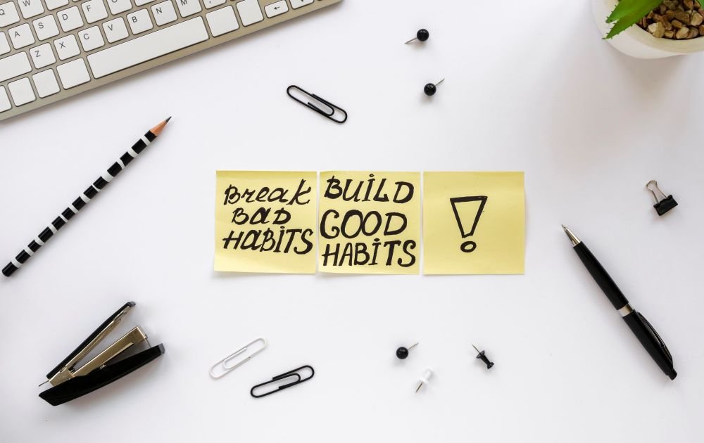 Sticky notes that say bread old habits, build good habits on top of a desk