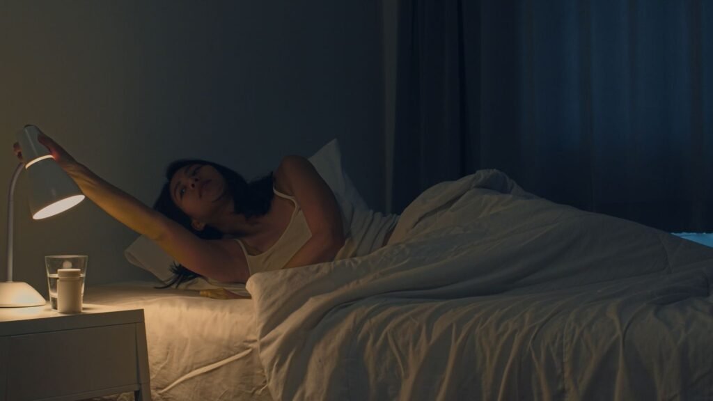 Young woman turning on her bedroom lamp after a good night sleep