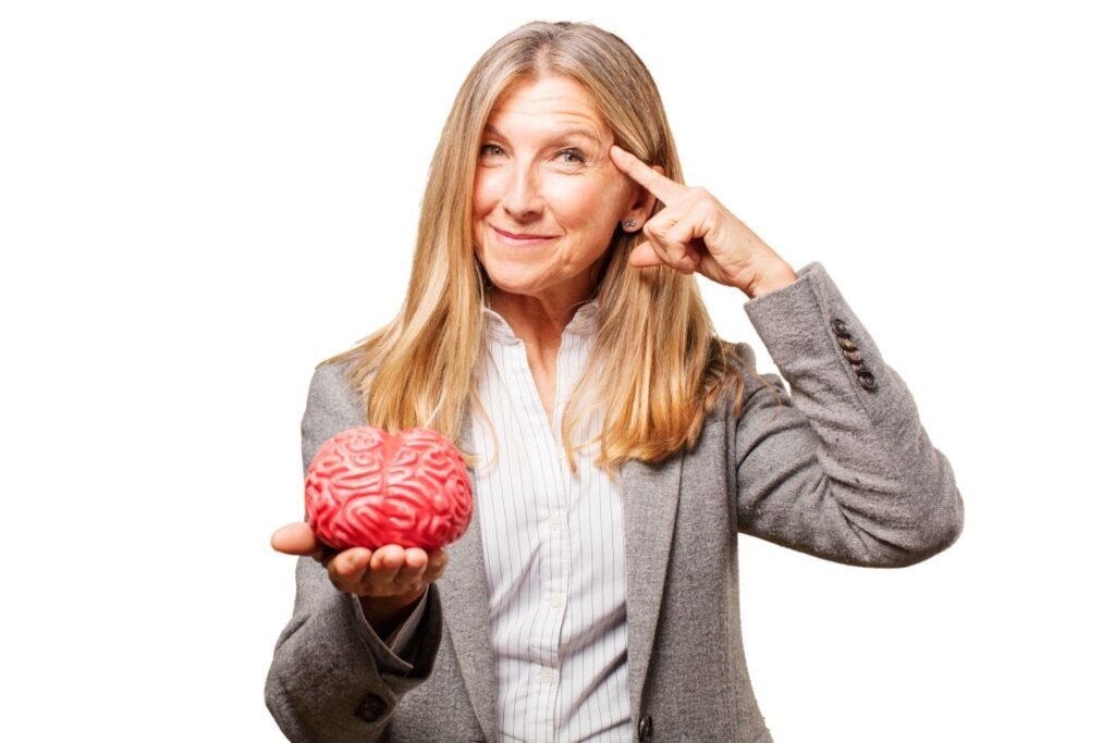 Woman holding a model of a brain in one hand and pointing at her head with another hand