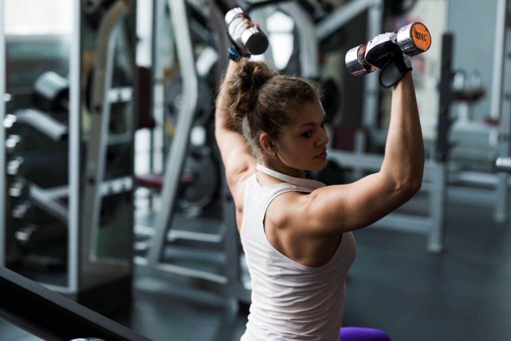 Strong woman exercising with dumbbells in the gym