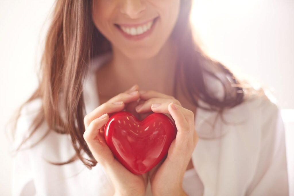 Young woman holding a red plastic heart in her hands