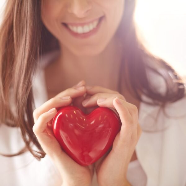 Young woman holding a red plastic heart in her hands