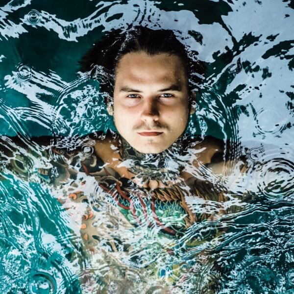 Young man submerged in cold water doing a cold plunge