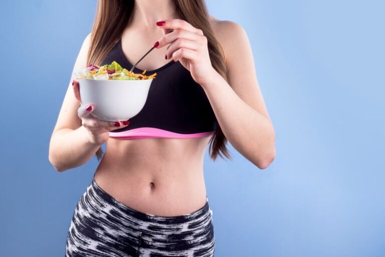 Fit woman in sport clothes holding a salad bowl for weight loss