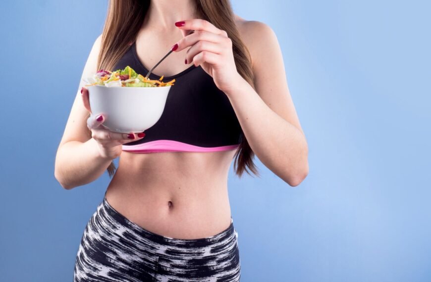 Fit woman in sport clothes holding a salad bowl for weight loss