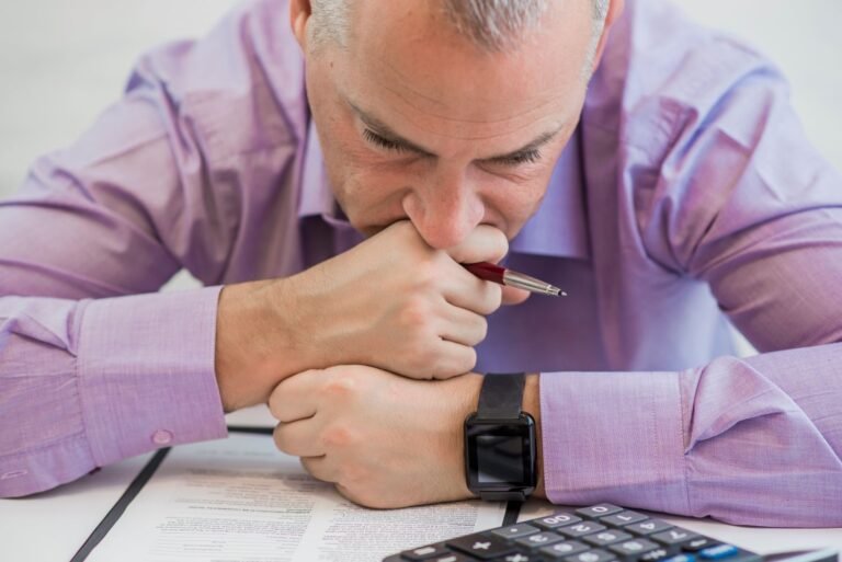 Stressed man is looking down on papers and calculator obviously seemed stressed about money