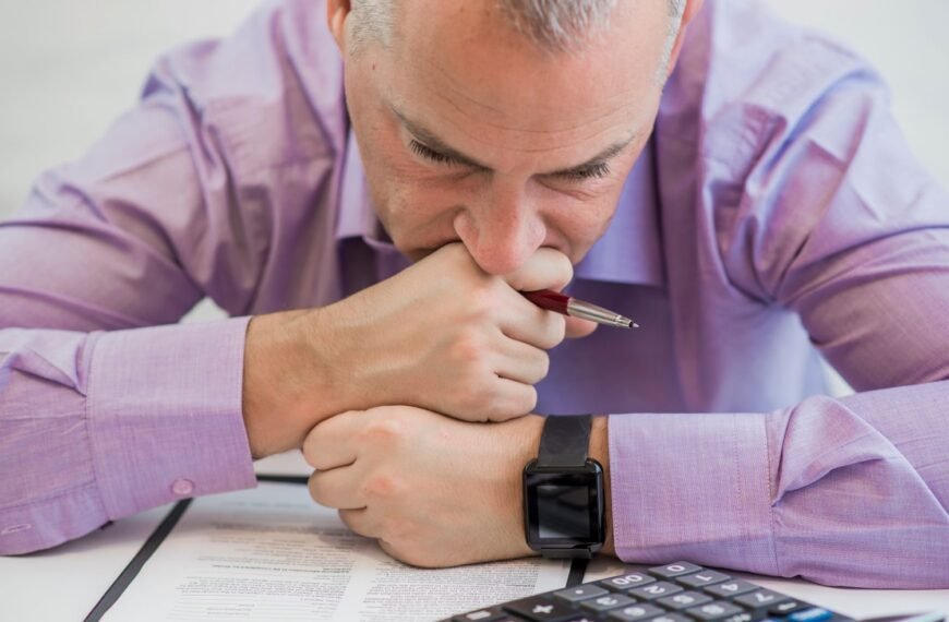 Stressed man is looking down on papers and calculator obviously seemed stressed about money