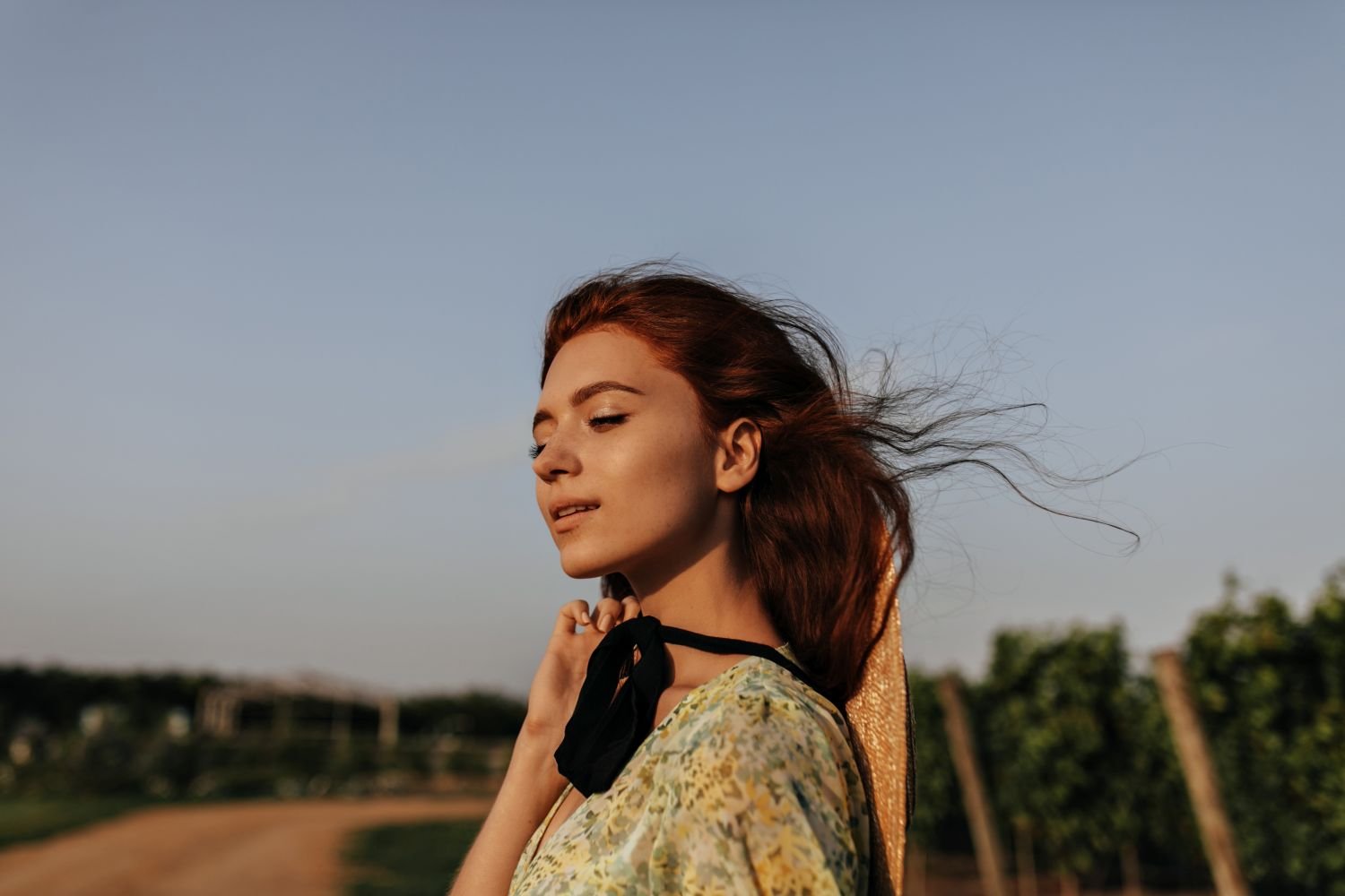 A young woman taking a deep breath outdoors, eyes closed, calm expression — illustrating tools for how to manage stress and anxiety using neuroscience