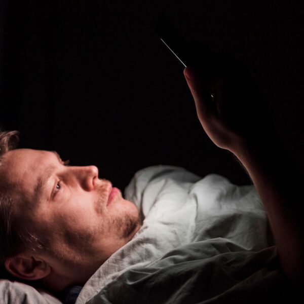 A man looking at a phone late at night with the glow illuminating their face — illustrating digital dopamine addiction and the need to fix dopamine levels