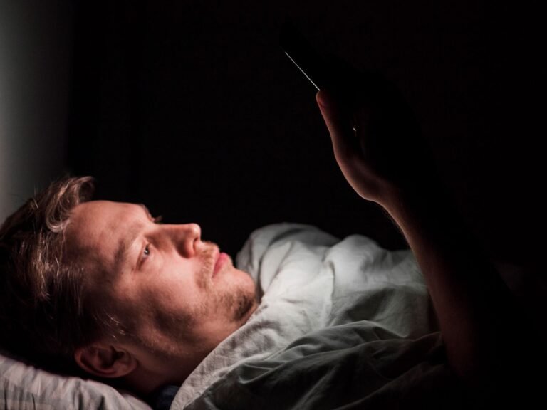 A man looking at a phone late at night with the glow illuminating their face — illustrating digital dopamine addiction and the need to fix dopamine levels