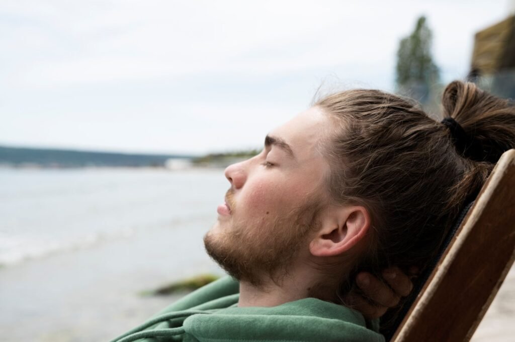 Person taking a deep breath outdoors, eyes closed, calm expression — illustrating tools for how to manage stress and anxiety using neuroscience