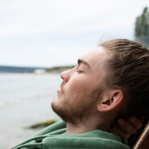 Person taking a deep breath outdoors, eyes closed, calm expression — illustrating tools for how to manage stress and anxiety using neuroscience